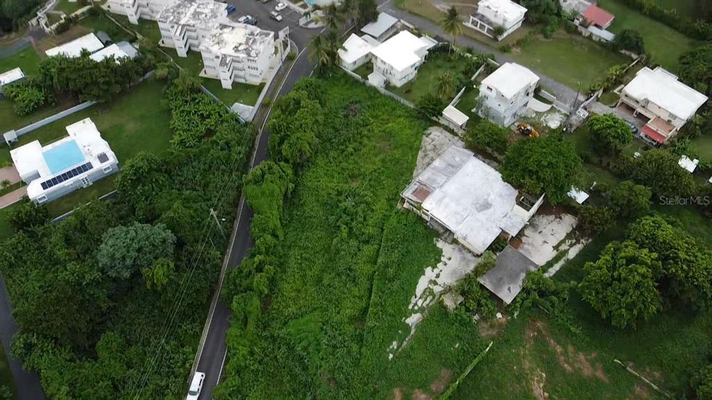 An aerial view shows a vacant, overgrown lot situated between several residential buildings and roads — PR-648 MAR CHIQUITA, MANATI, PR