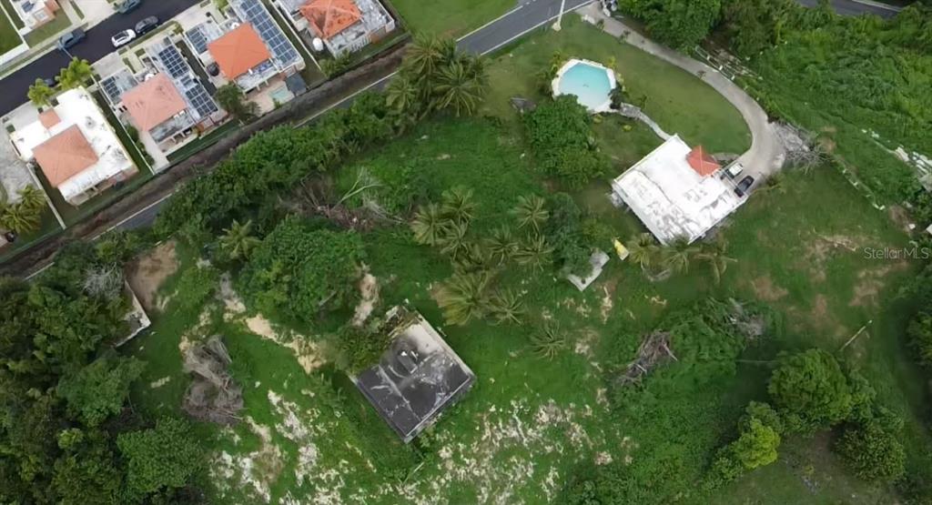 An aerial view shows a large grassy lot with two houses, trees, and a pool — PR-648 MAR CHIQUITA, MANATI, PR