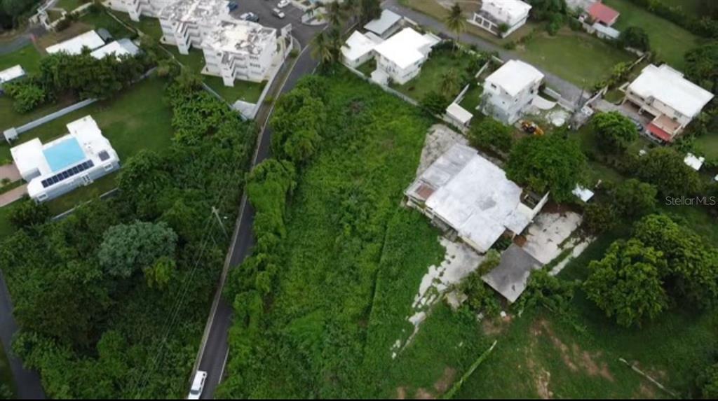 An aerial view shows a residential lot with a house, dense vegetation, and surrounding properties — PR-648 MAR CHIQUITA, MANATI, PR