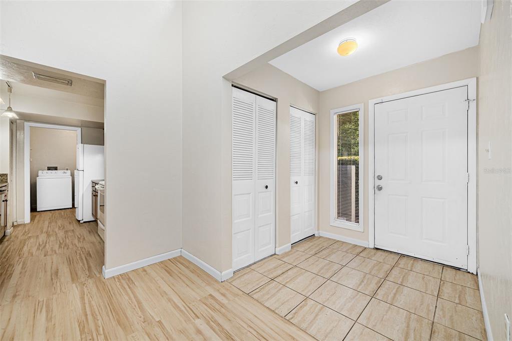An entryway with tiled flooring, two white louvered closets, and a view into a laundry room — 1854 NW 41ST PLACE, GAINESVILLE, FL