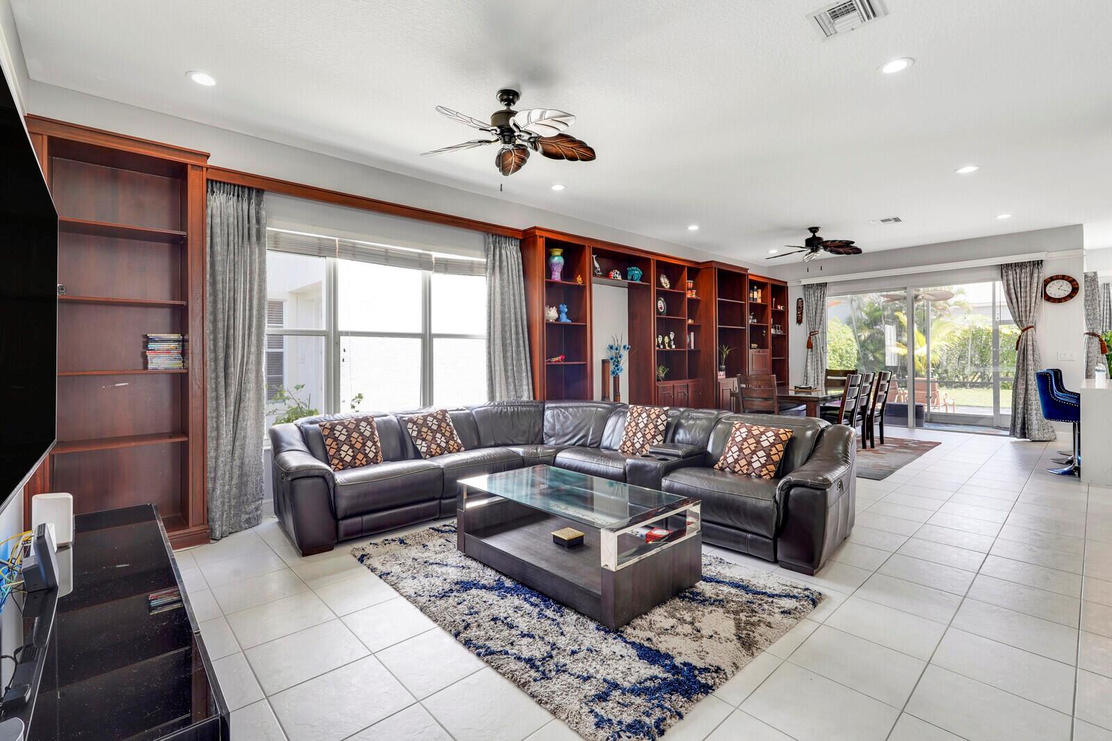 A living room features a large leather sectional, a glass coffee table, and built-in shelving — 19084 Skyridge Circle, Boca Raton FL 33498, BOCA RATON, FL