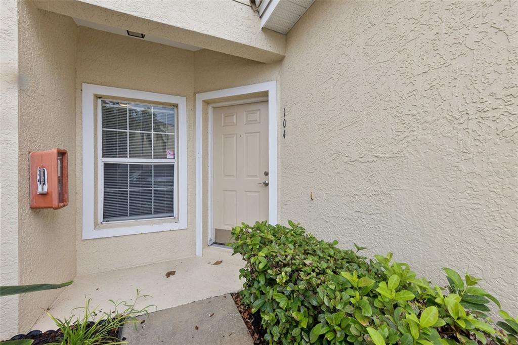 The exterior view shows a beige stucco building entrance with a front door and window — 674 SANDY NECK LANE UNIT 104, ALTAMONTE SPRINGS, FL