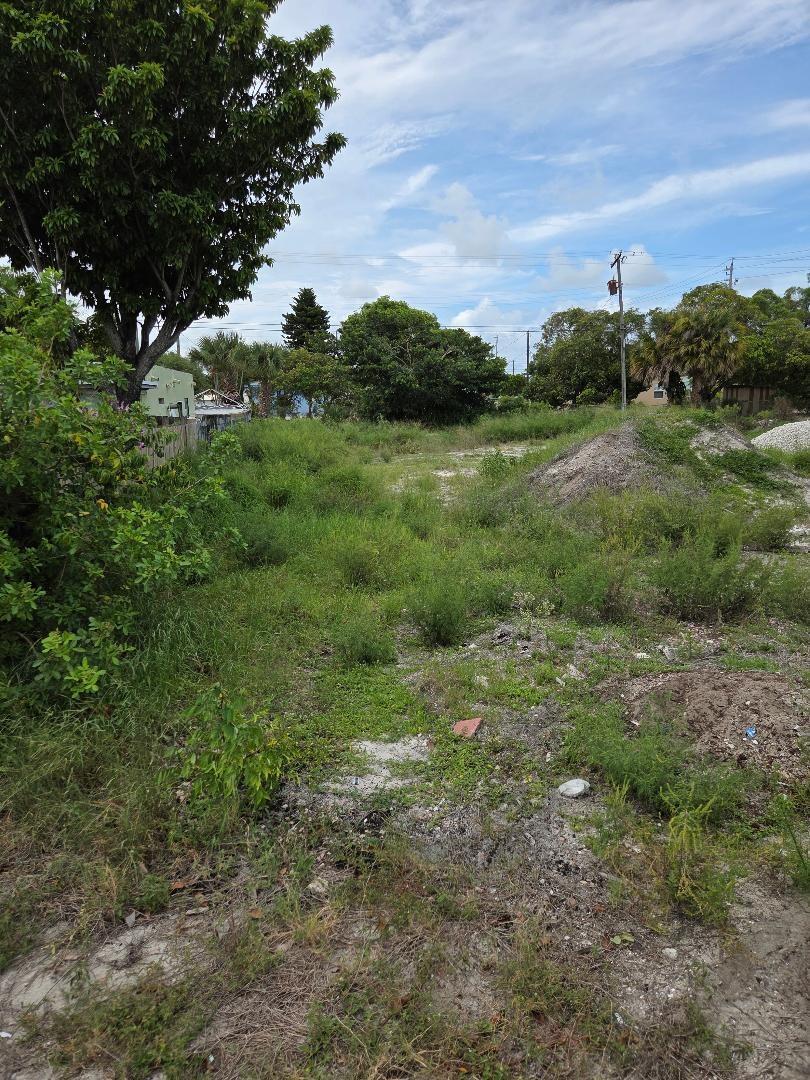An overgrown vacant lot features patches of grass, sandy soil, and a small dirt mound — 1114 W 28th Street, Riviera Beach FL 33404, RIVIERA BEACH, FL