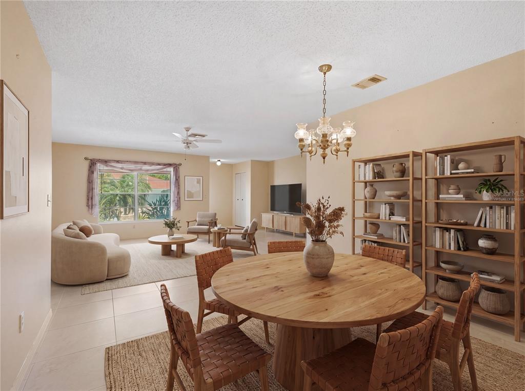 A dining area with a round wooden table sits in front of a living room — 1027 BLUEWATER DRIVE, SUN CITY CENTER, FL