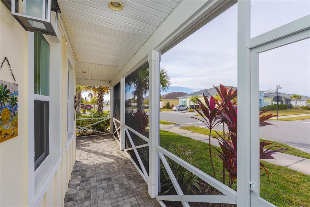A screened-in porch with paver flooring overlooks a suburban street and neighborhood houses — 572 LANDSHARK BOULEVARD, DAYTONA BEACH, FL