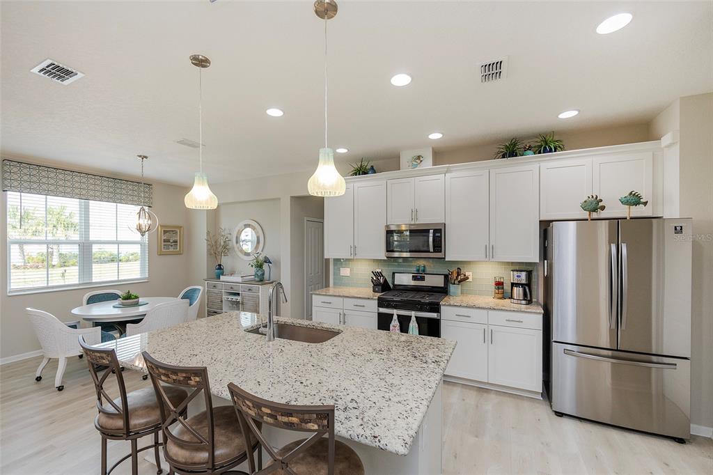 A kitchen features white cabinets, granite countertops, a center island, and stainless steel appliances — 572 LANDSHARK BOULEVARD, DAYTONA BEACH, FL