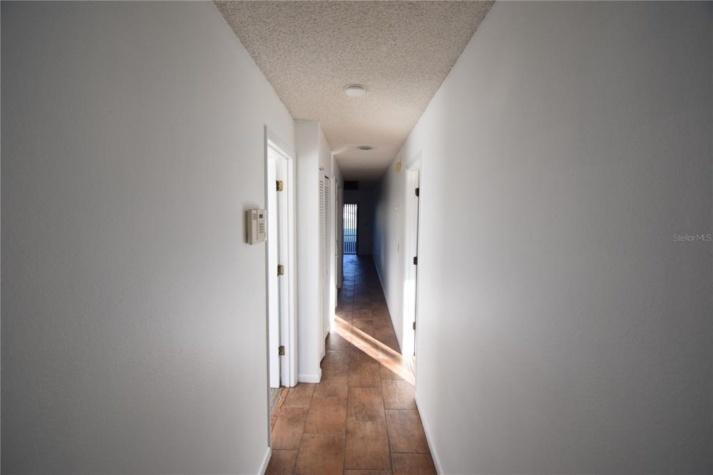 A long hallway with white walls, brown tile flooring, and a textured popcorn ceiling — 6055 TOPHER TRAIL UNIT 6055, MULBERRY, FL