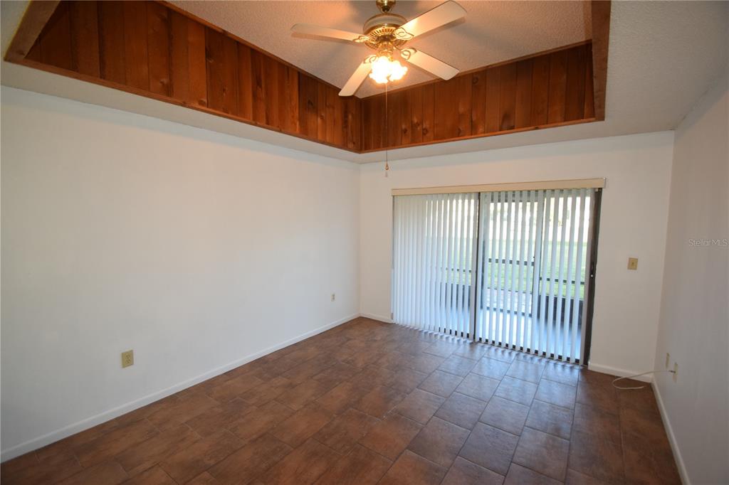 A room with tile flooring, a wood-paneled tray ceiling, a ceiling fan, and sliding doors — 6055 TOPHER TRAIL UNIT 6055, MULBERRY, FL