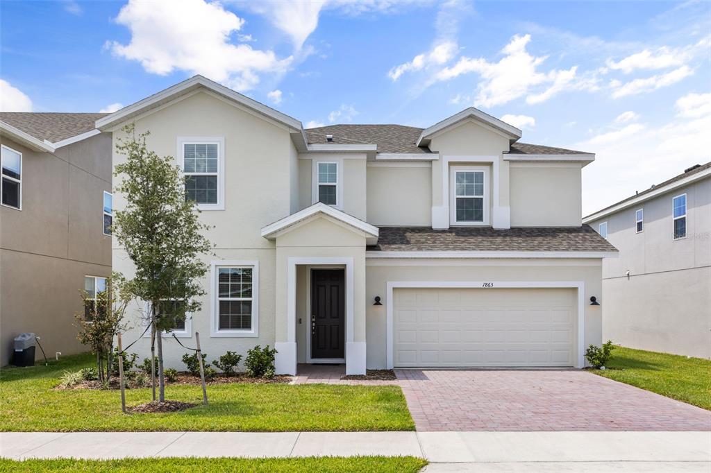 A two-story suburban house with a beige stucco exterior, a two-car garage, and a driveway — 1863 CHURCH LAKE STREET, GROVELAND, FL