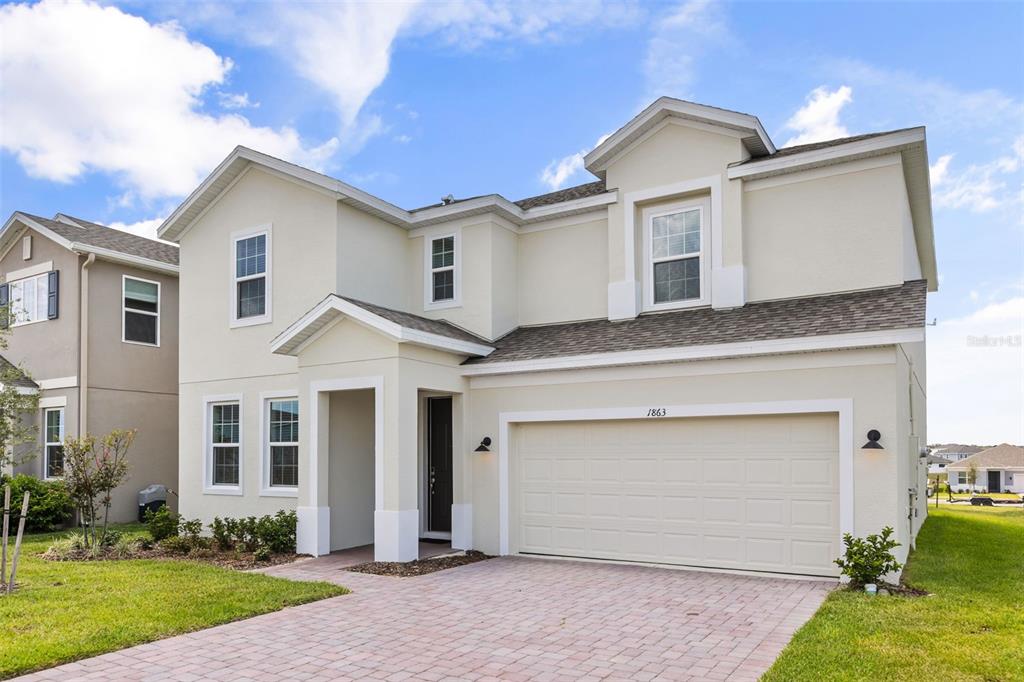A two-story suburban house with a beige stucco exterior, a two-car garage, and a driveway — 1863 CHURCH LAKE STREET, GROVELAND, FL