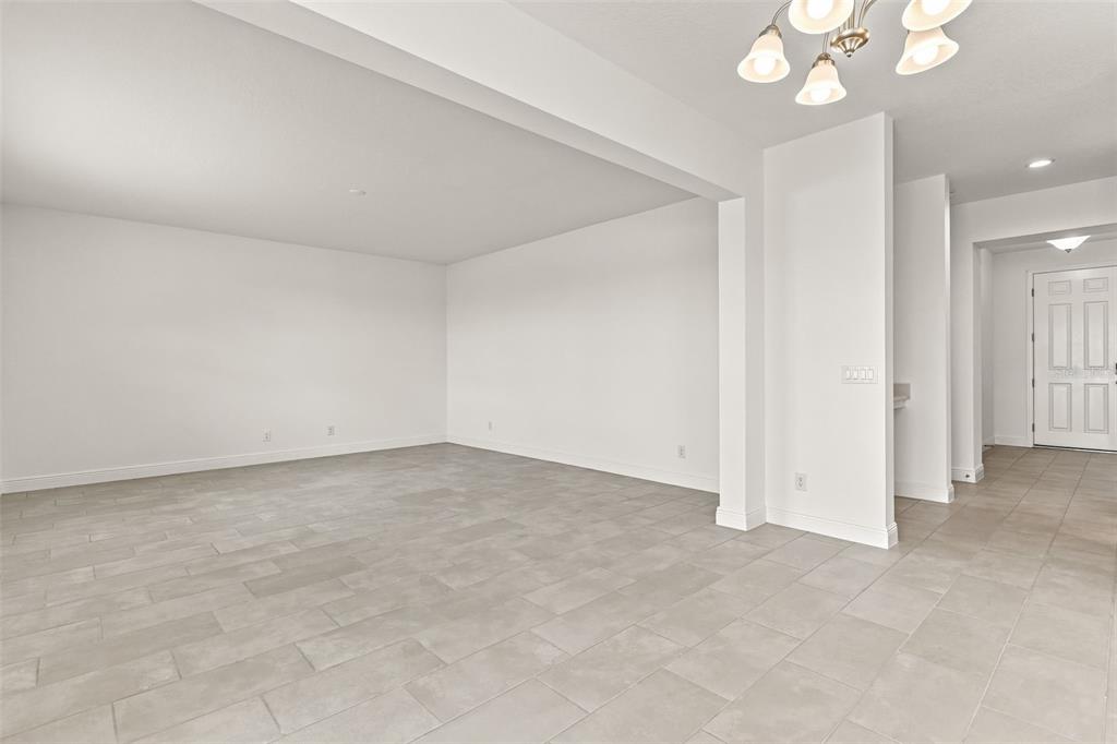 An empty room with light gray tile flooring, white walls, and a modern chandelier — 1863 CHURCH LAKE STREET, GROVELAND, FL
