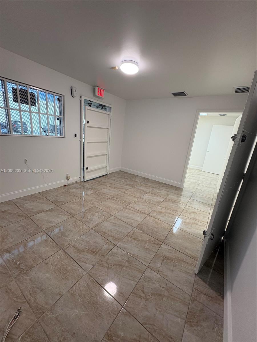This room features light-colored tile flooring, white walls, a ceiling light, and an exit door — 11467 NW 34th St # 11471, Doral FL 33178, DORAL, FL