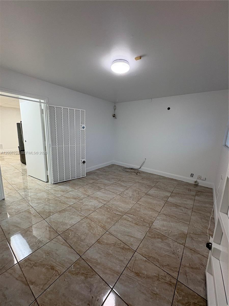 An empty room features white walls, a tiled floor, and a white metal security gate — 11467 NW 34th St # 11471, Doral FL 33178, DORAL, FL
