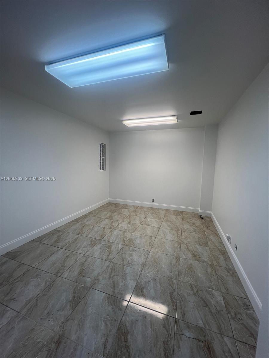 An empty room features white walls, tiled flooring, and two rectangular ceiling light fixtures — 11467 NW 34th St # 11471, Doral FL 33178, DORAL, FL