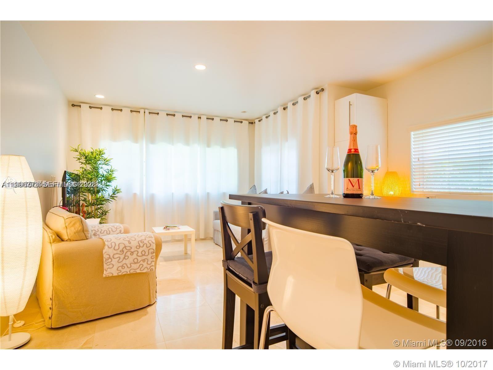 A living room features a beige armchair, a small white table, and a dark bar table — 929 Michigan Ave # 1, Miami Beach FL 33139, MIAMI BEACH, FL