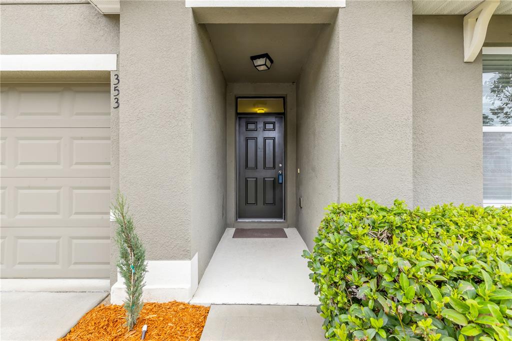 A front entryway features a dark door, a concrete walkway, and a small shrub — 353 ADMIRALTY COURT, EDGEWATER, FL