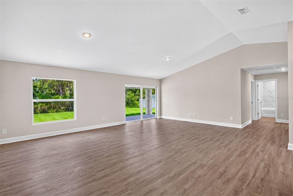 An open-concept living room and kitchen featuring light-colored furniture, wood-look flooring, and recessed lighting — 18367 BUTTERCUP AVENUE, PORT CHARLOTTE, FL