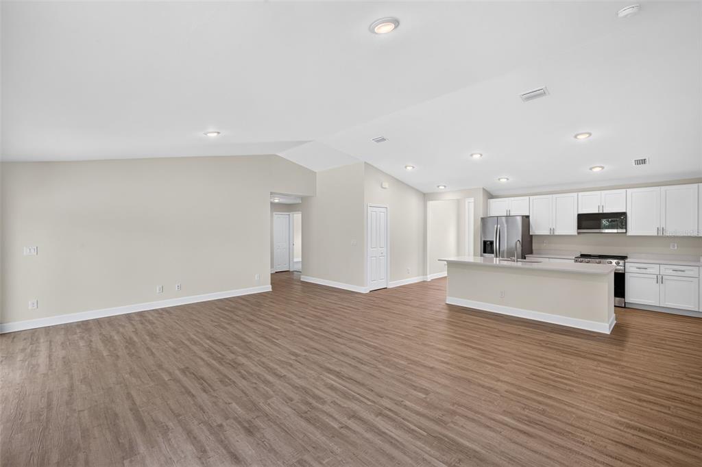 A living room with light-colored furniture, a round coffee table, and a view of trees — 18367 BUTTERCUP AVENUE, PORT CHARLOTTE, FL