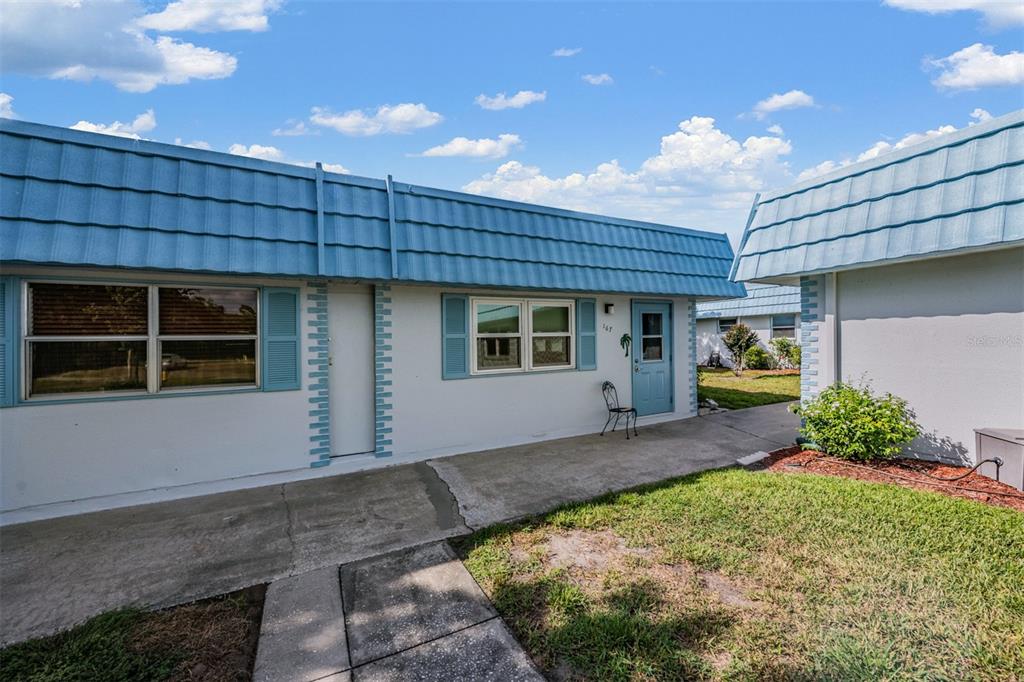 A single-story building with a blue mansard roof, white stucco walls, and a concrete walkway — 302 ANDOVER PLACE S UNIT 167, SUN CITY CENTER, FL
