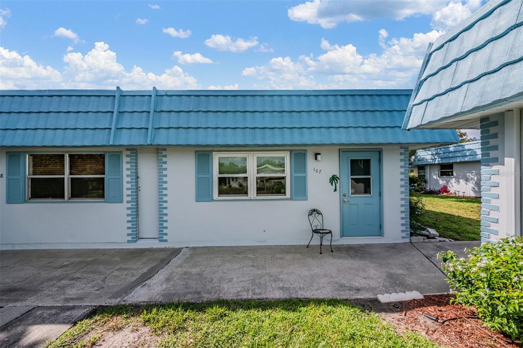 A single-story white house with a blue metal roof and a matching blue front door — 302 ANDOVER PLACE S UNIT 167, SUN CITY CENTER, FL