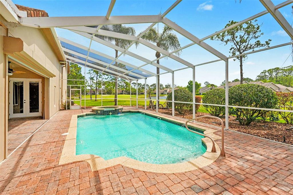 A screened-in pool and spa area with brick pavers and a view of a golf course — 3114 SPRUCE CREEK BOULEVARD, PORT ORANGE, FL