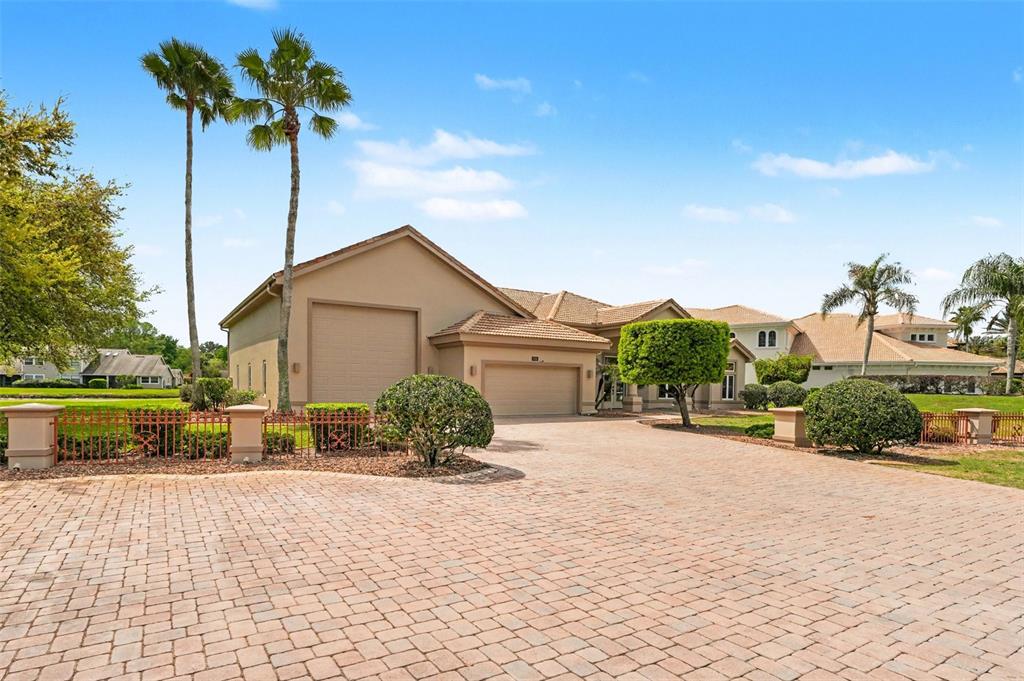 A tan house with a paved driveway, a multi-car garage, and palm trees — 3114 SPRUCE CREEK BOULEVARD, PORT ORANGE, FL