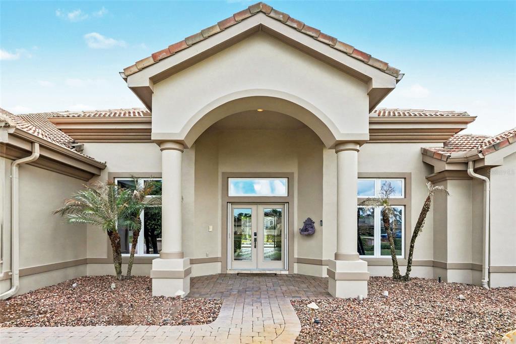 The exterior of a beige house features a covered entryway with two columns and double doors — 3114 SPRUCE CREEK BOULEVARD, PORT ORANGE, FL