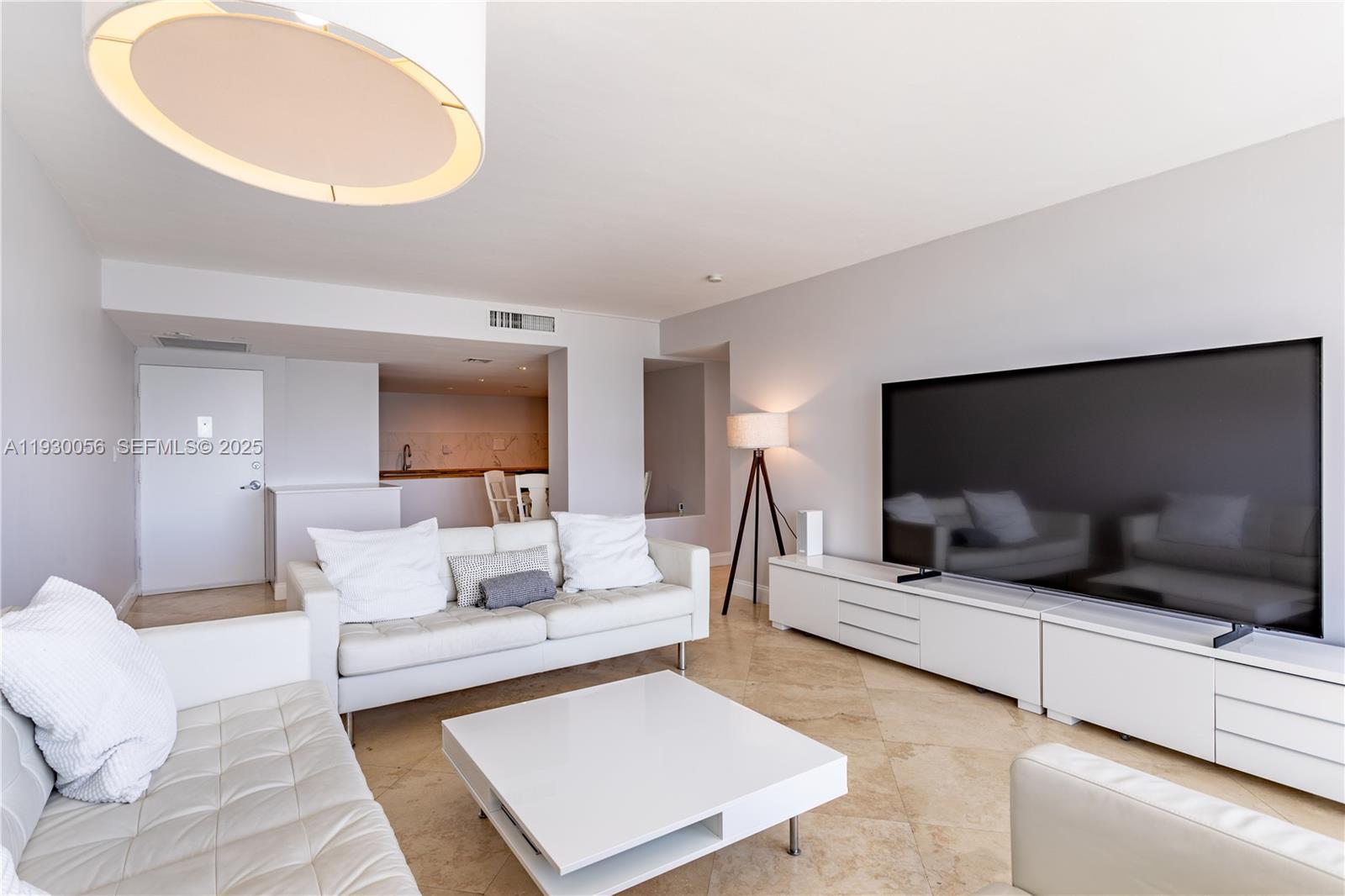 A modern living room features white leather sofas, a coffee table, and a large television — 1200 West Ave # 526, Miami Beach FL 33139, MIAMI BEACH, FL