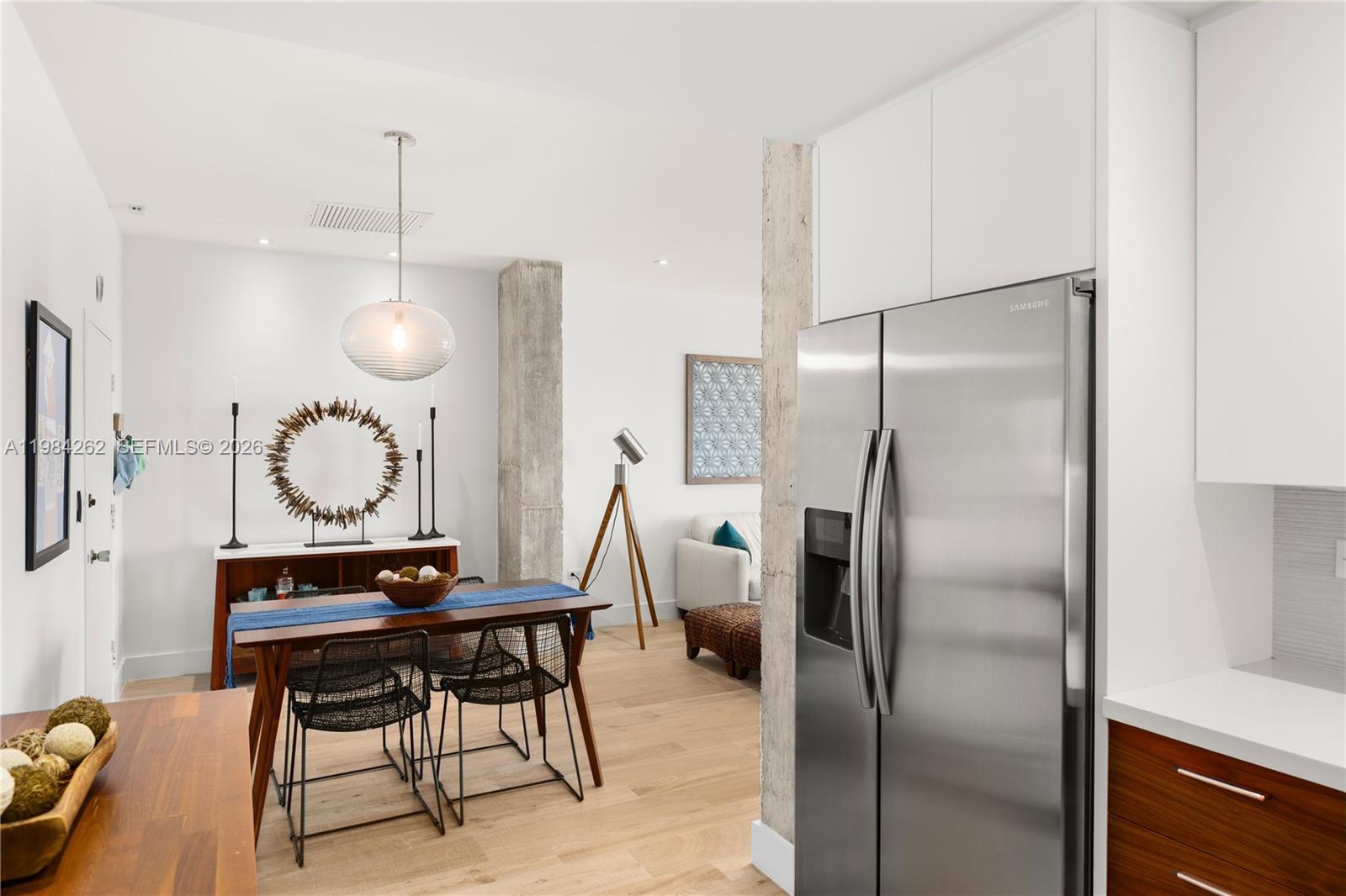 A modern dining area features a wooden table, wire chairs, and a stainless steel refrigerator — 5555 Collins Ave # 17J, Miami Beach FL 33140, MIAMI BEACH, FL