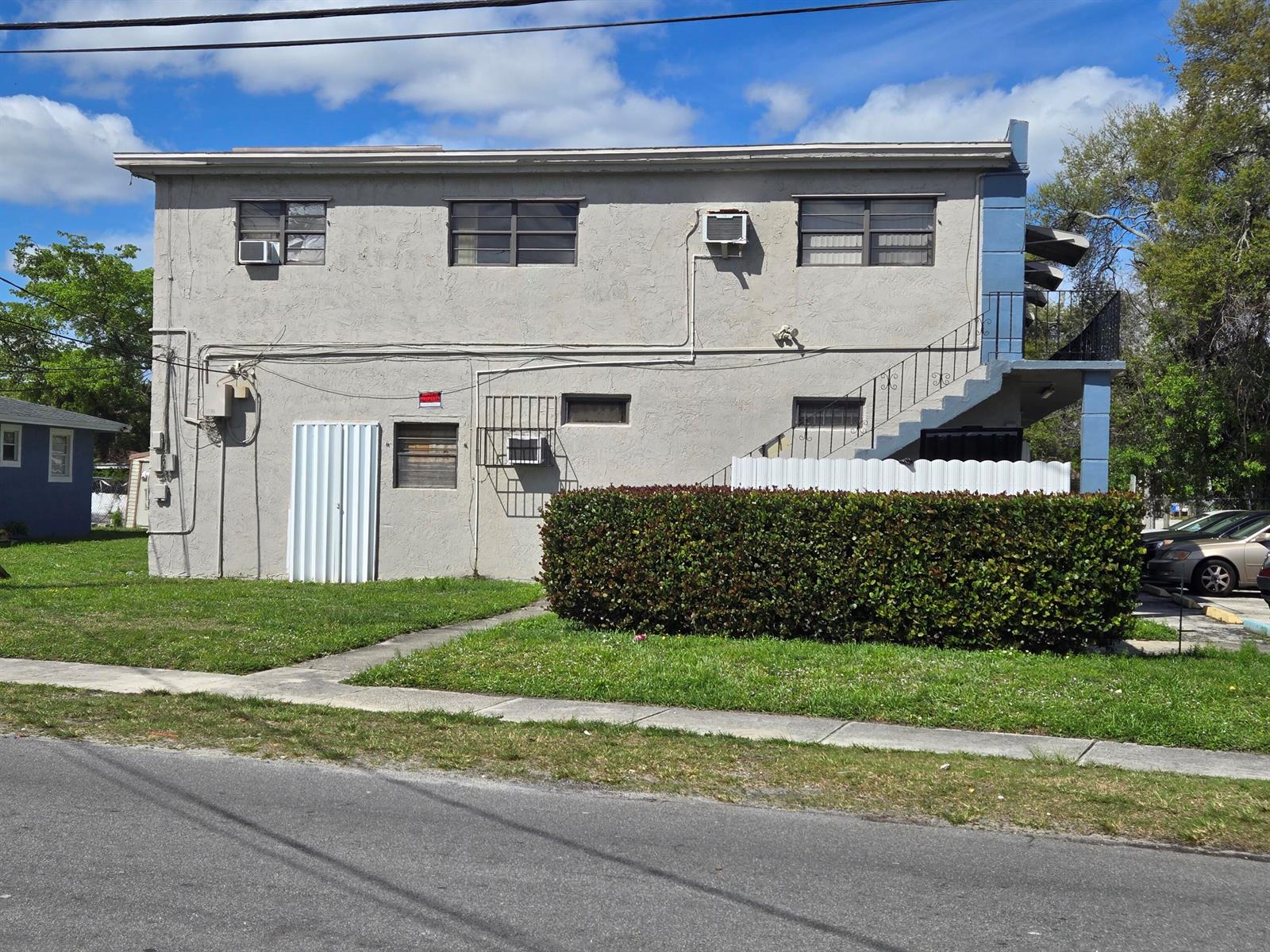 A two-story stucco apartment building features an exterior staircase and a hedge-lined front yard — 602 NW 1st Street, Dania Beach FL 33004, DANIA BEACH, FL