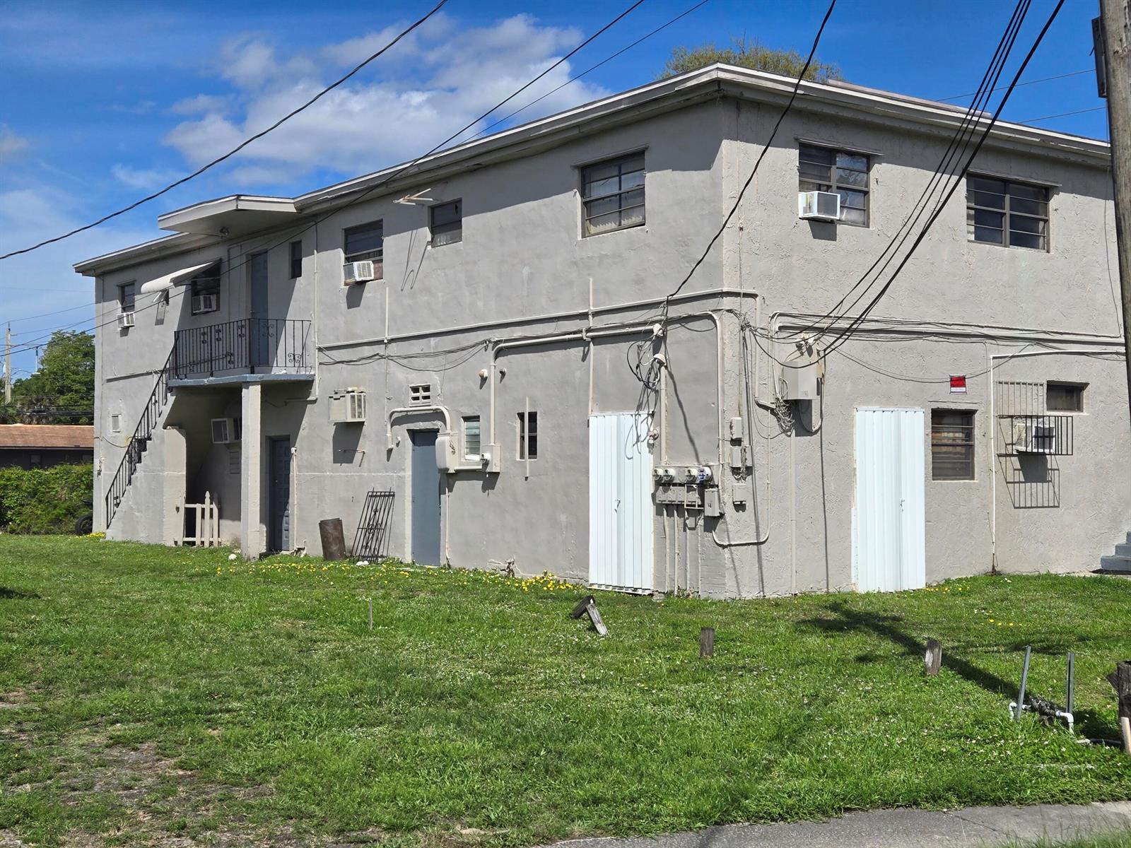 A two-story gray stucco apartment building features exterior staircases, multiple doors, and window air conditioners — 602 NW 1st Street, Dania Beach FL 33004, DANIA BEACH, FL