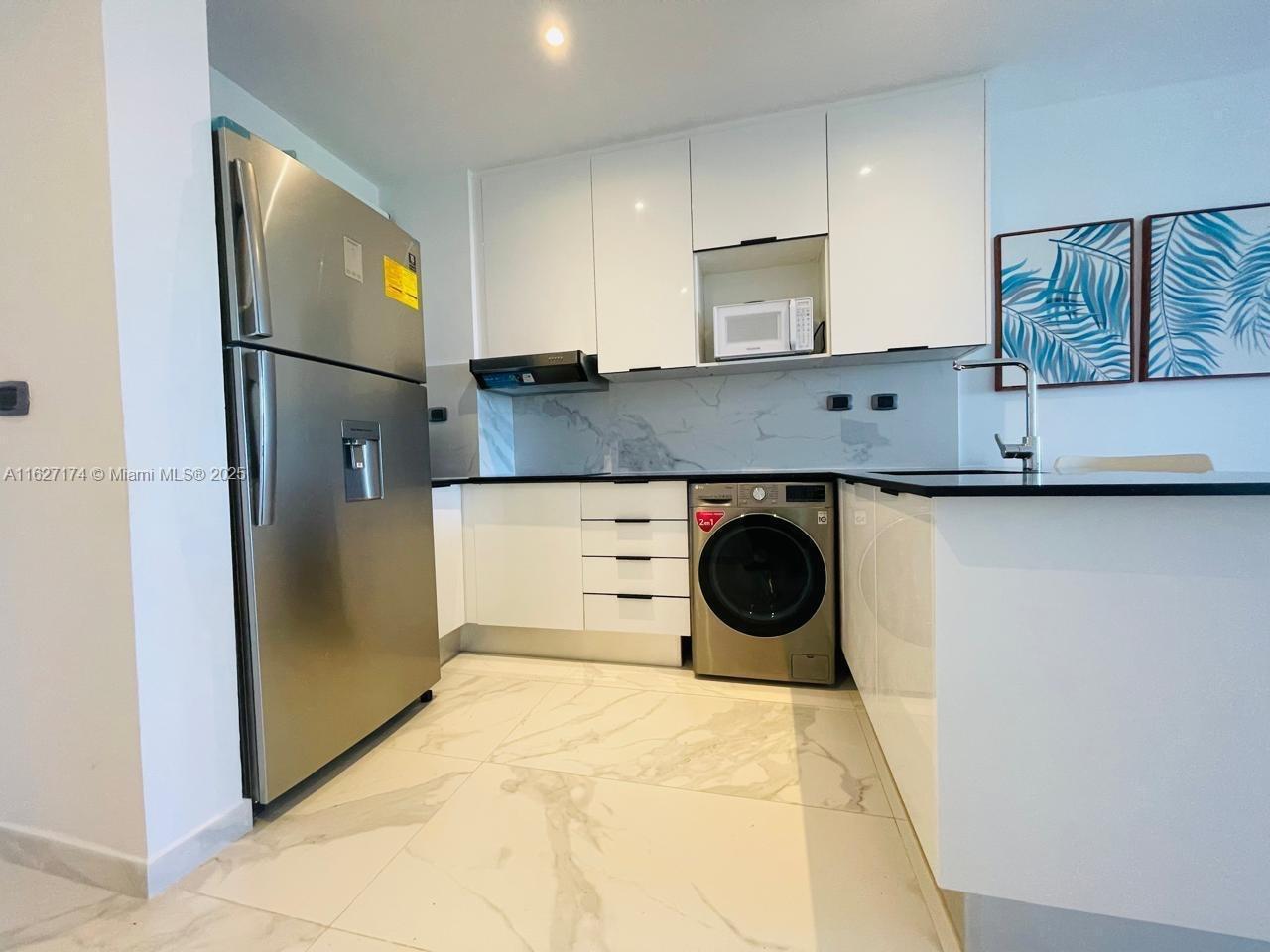 A modern kitchen features white cabinetry, stainless steel appliances, and marble-patterned tile flooring — Av. Hard Rock Punta Cana 23000 #PH-510 , Dominican Republic, DR, DR