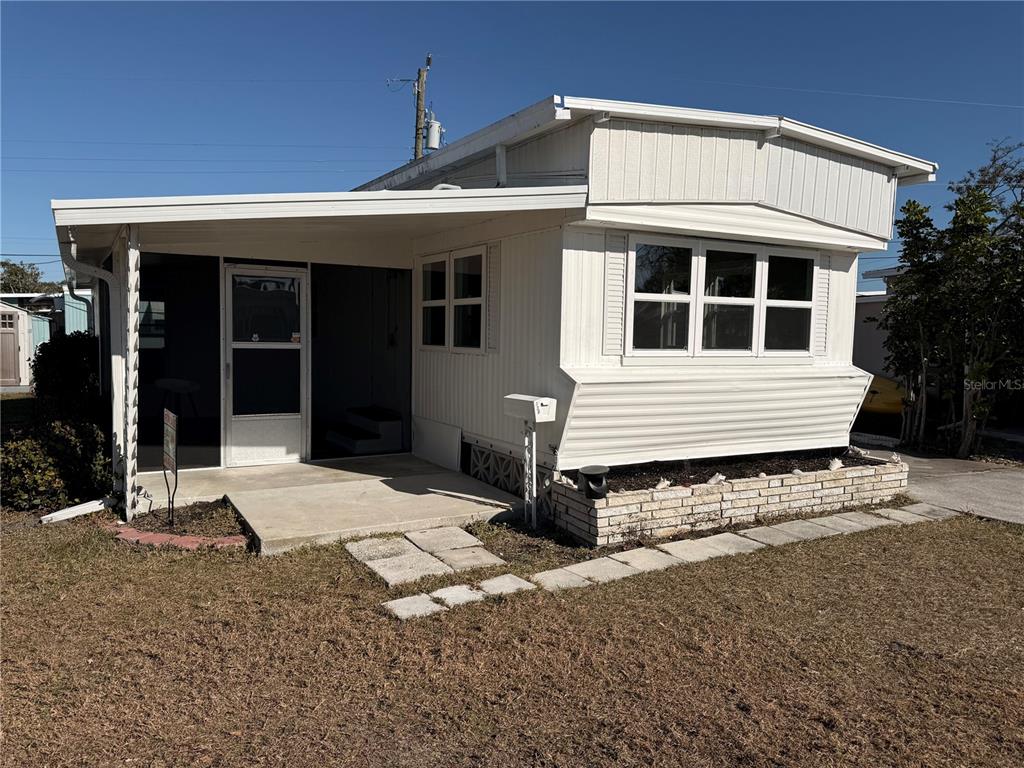 A white mobile home features a screened-in porch and a brick-bordered garden bed — 1800 ENGLEWOOD ROAD UNIT 136, ENGLEWOOD, FL