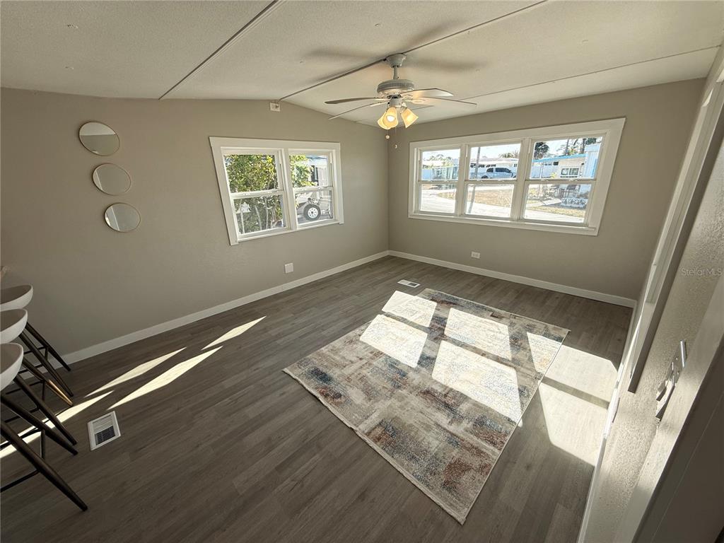 A living room with light gray walls, wood-look flooring, a ceiling fan, and a rug — 1800 ENGLEWOOD ROAD UNIT 136, ENGLEWOOD, FL
