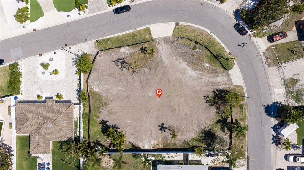 An aerial view shows a vacant, cleared residential lot situated on a curved street — 911 BOCA CIEGA ISLE DRIVE, ST PETE BEACH, FL