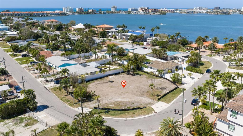 An aerial view shows a vacant, sandy residential lot situated near a coastal waterway — 911 BOCA CIEGA ISLE DRIVE, ST PETE BEACH, FL