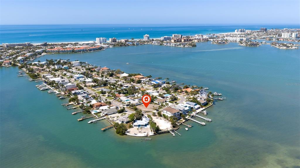 An aerial view shows a vacant waterfront lot marked with a red pin on an island — 911 BOCA CIEGA ISLE DRIVE, ST PETE BEACH, FL