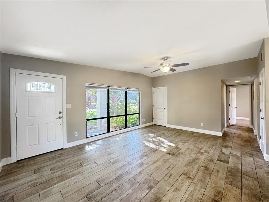 A living room features light gray walls, wood-look tile flooring, a ceiling fan, and windows — 3628 DAGON STREET, ORLANDO, FL