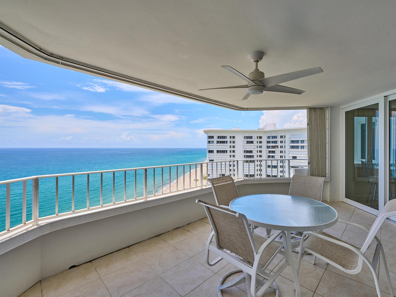 A balcony with a table and chairs overlooking the ocean and a neighboring building — 500 S Ocean Boulevard # 2106, Boca Raton FL 33432, BOCA RATON, FL