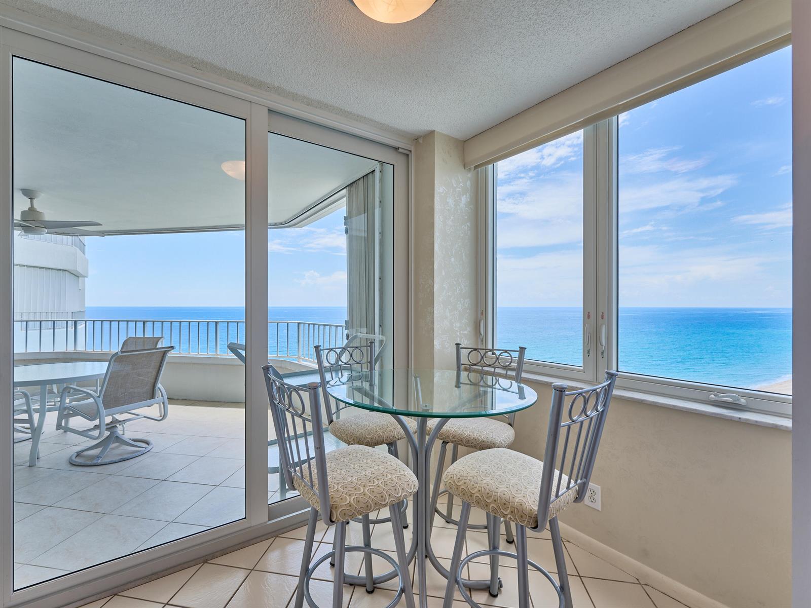 A dining area with a glass table and four chairs overlooks the ocean through windows — 500 S Ocean Boulevard # 2106, Boca Raton FL 33432, BOCA RATON, FL