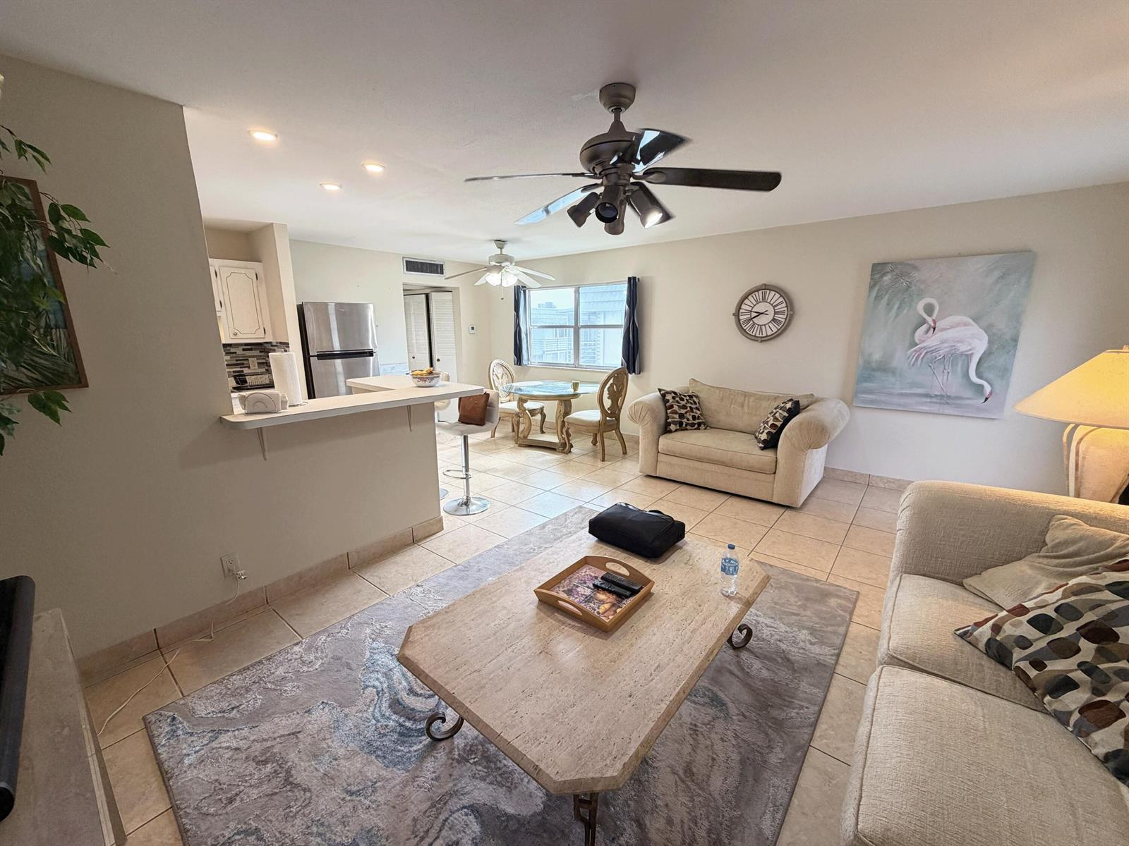 An open-concept living room and kitchen area features tile flooring and a ceiling fan — 419 Brittany Drive, Delray Beach FL 33446, DELRAY BEACH, FL