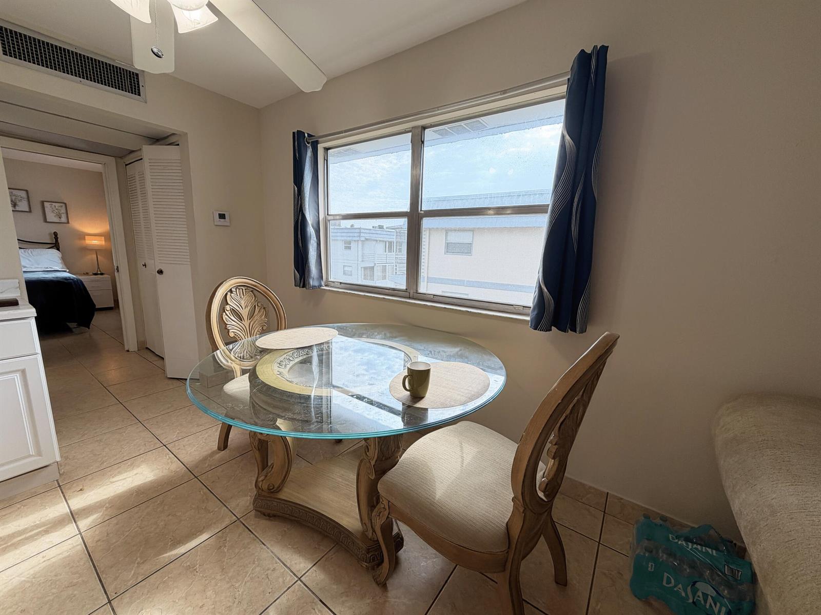 A dining area features a glass-topped table, two ornate chairs, and a window with curtains — 419 Brittany Drive, Delray Beach FL 33446, DELRAY BEACH, FL