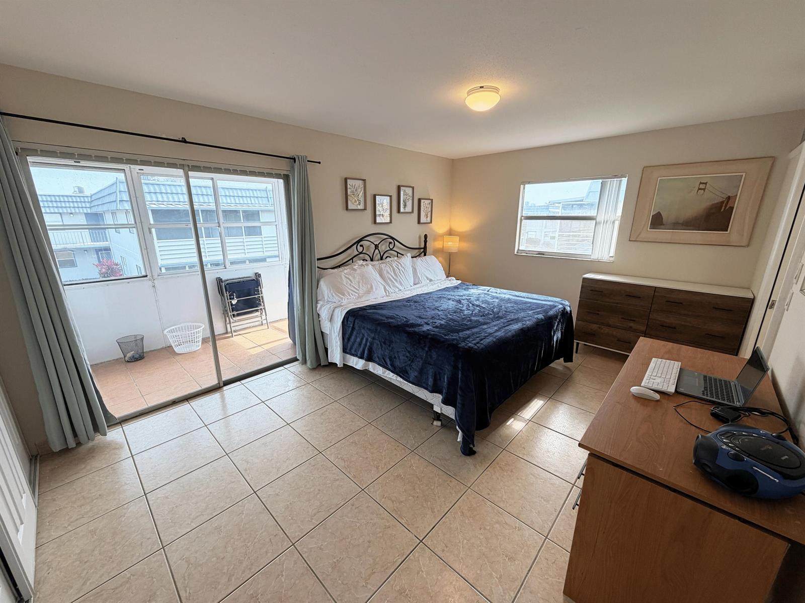 A bedroom with tile flooring, a bed, a dresser, a desk, and a sliding glass door — 419 Brittany Drive, Delray Beach FL 33446, DELRAY BEACH, FL