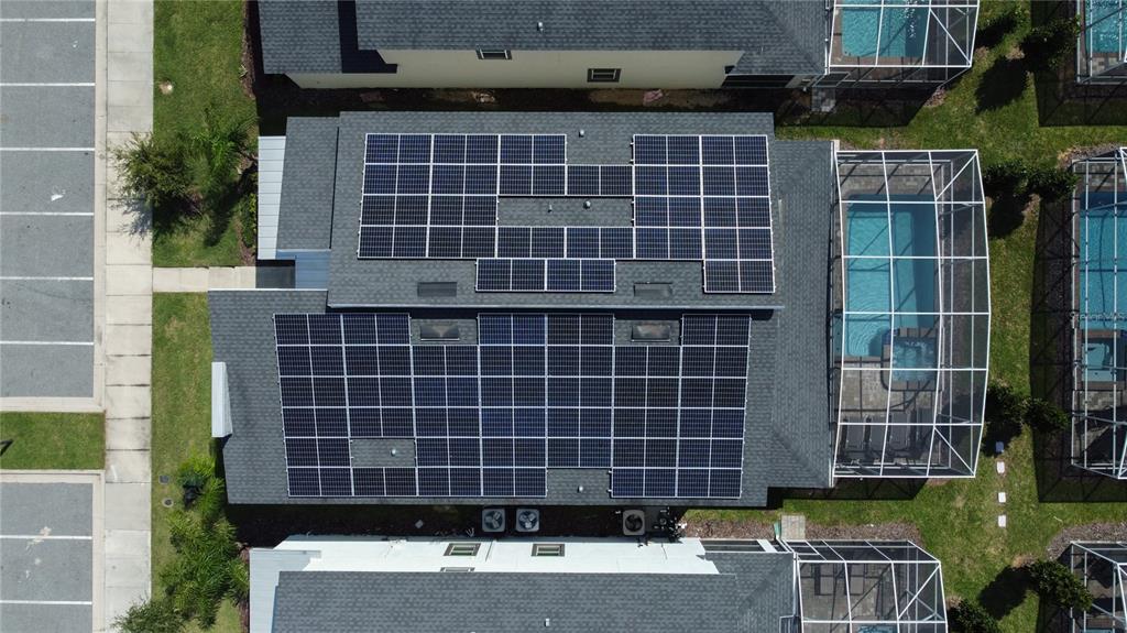 An aerial view shows a house roof covered with solar panels and a screened-in pool — 760 DROP SHOT DRIVE, DAVENPORT, FL