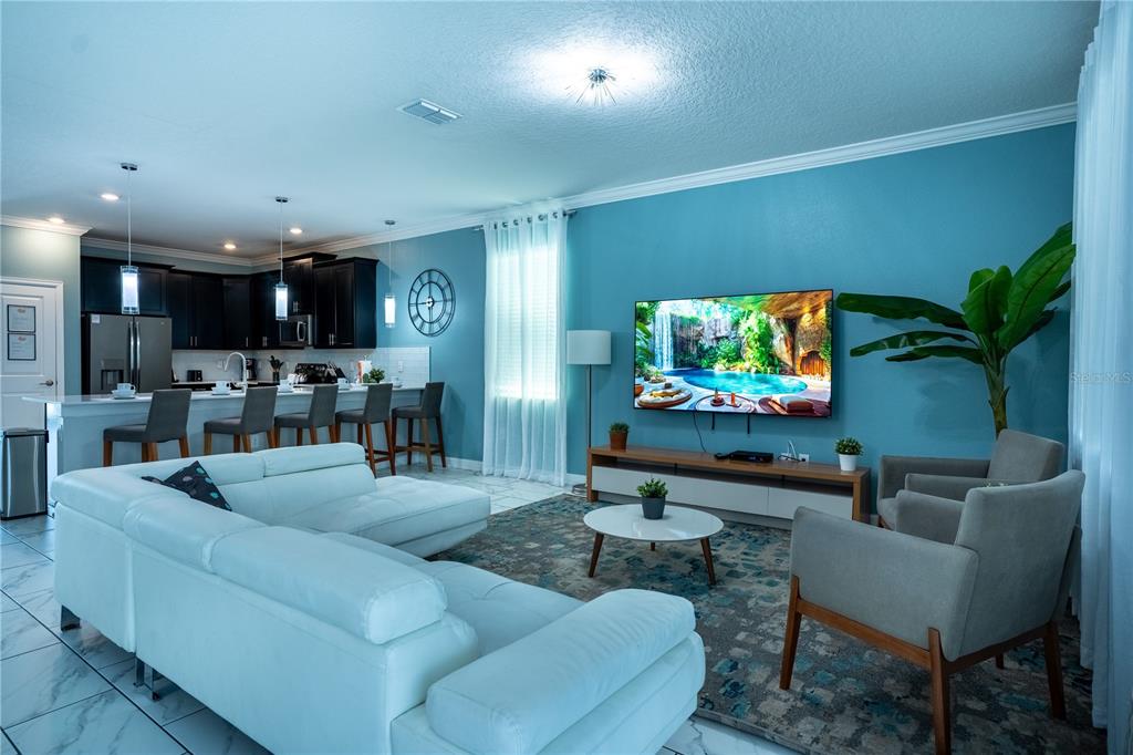 A living room with a white sectional, two armchairs, and a kitchen island with stools — 760 DROP SHOT DRIVE, DAVENPORT, FL