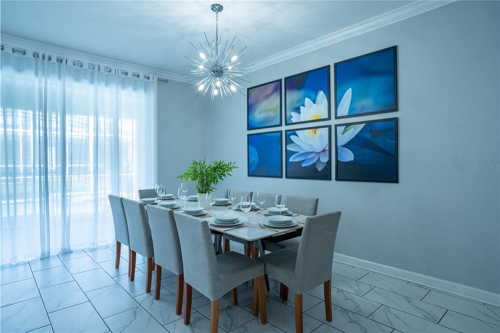A dining room features a modern starburst chandelier, a table for eight, and wall art — 760 DROP SHOT DRIVE, DAVENPORT, FL