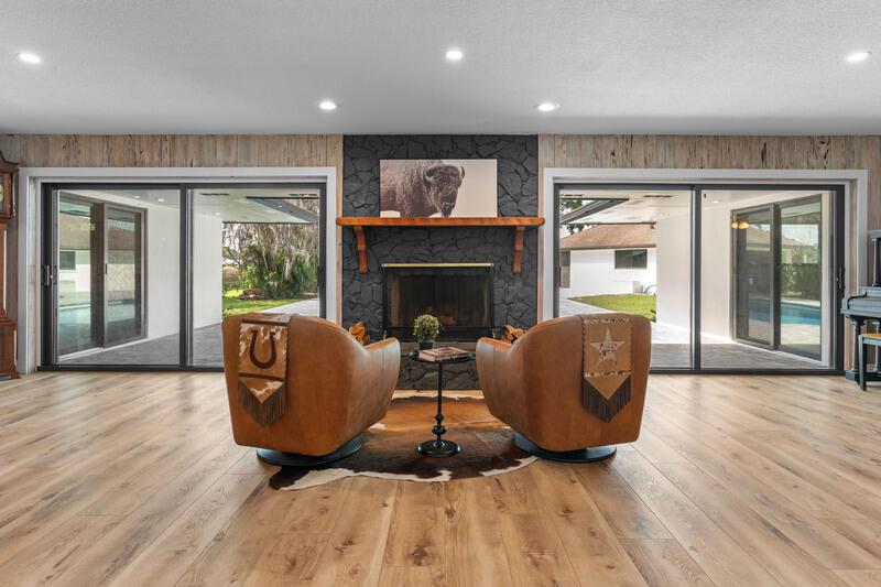 Two leather armchairs face a stone fireplace in a room with wood-look flooring and sliding doors — VERO BEACH, FL