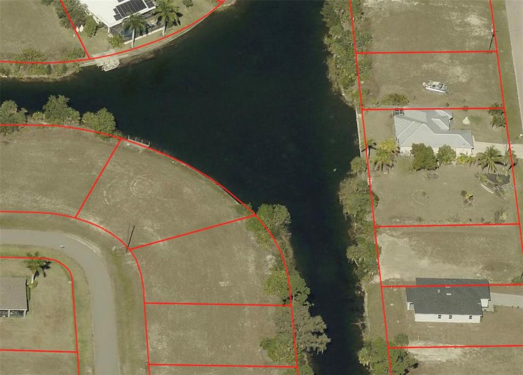 This aerial view shows several residential lots and a canal with red property boundary lines — 1133 NE 32ND TERRACE, CAPE CORAL, FL