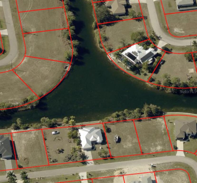 This aerial view shows a residential neighborhood with several houses situated along a canal — 1133 NE 32ND TERRACE, CAPE CORAL, FL