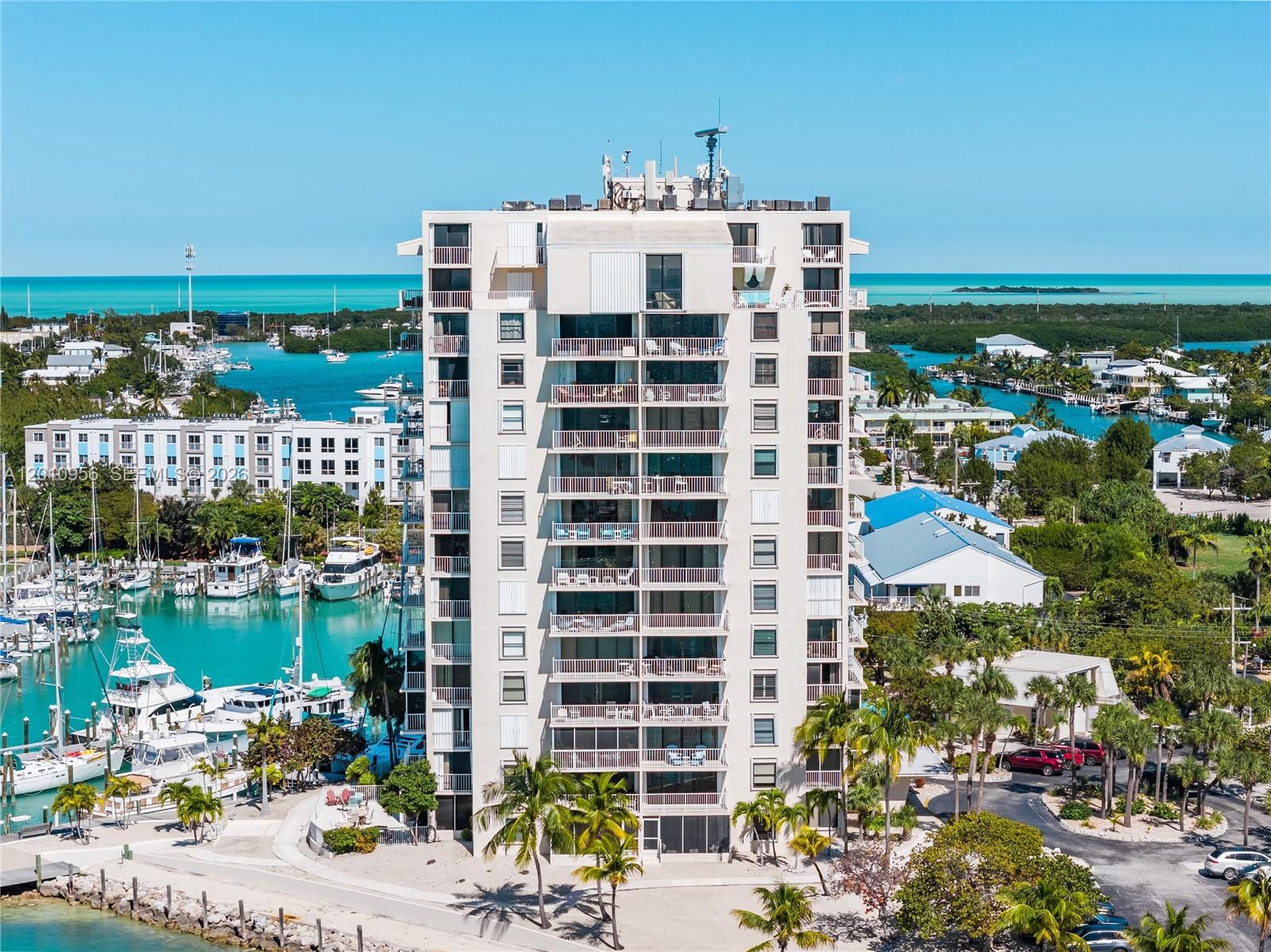 An aerial view shows a tall residential building situated next to a boat-filled marina — 2000 Coco Plum Dr # 601, Marathon FL 33050, MARATHON, FL